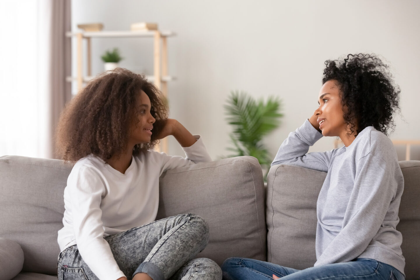 Young African American teenager speaking with mother on couch