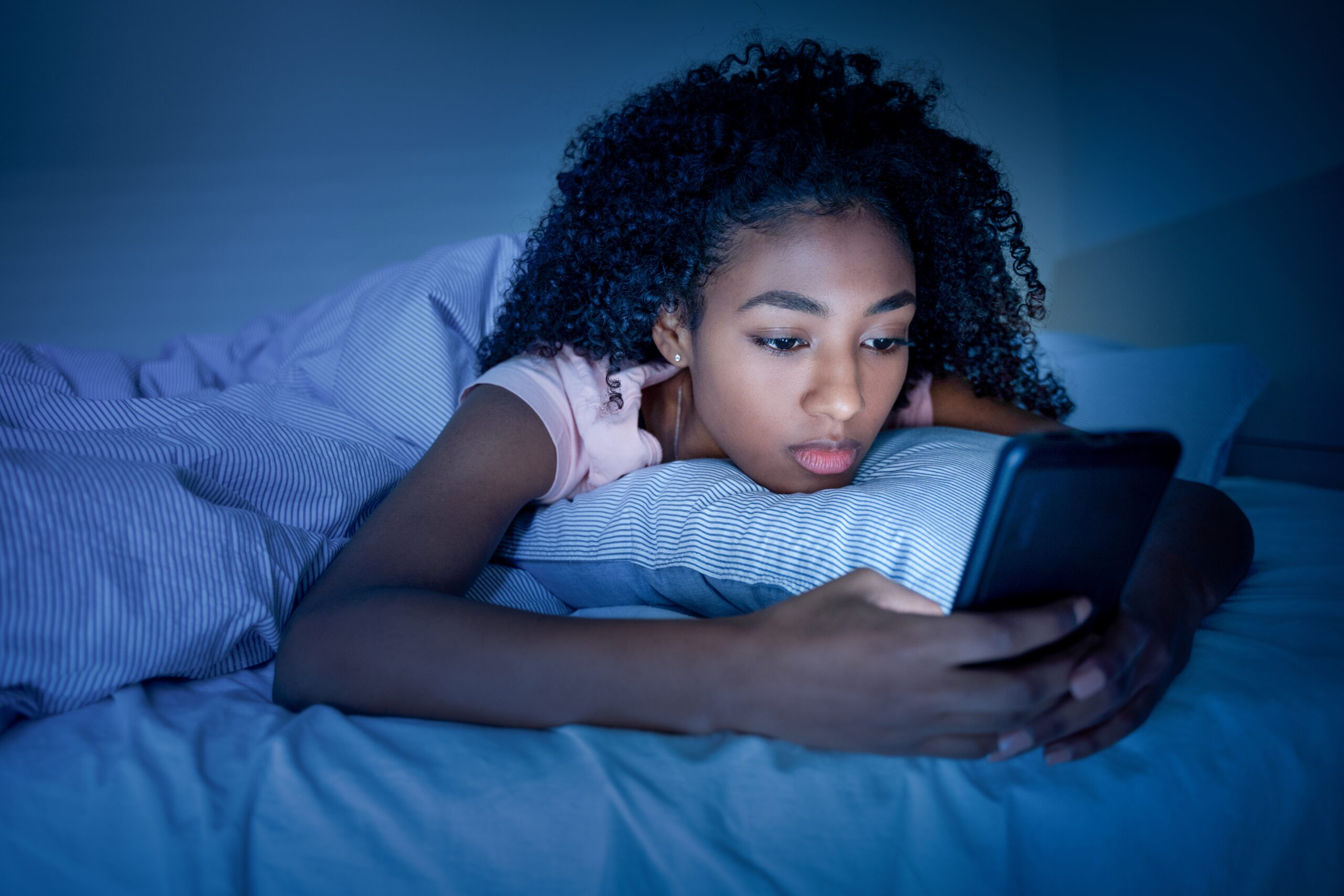 Teenage girl using smartphone in bed before sleeping