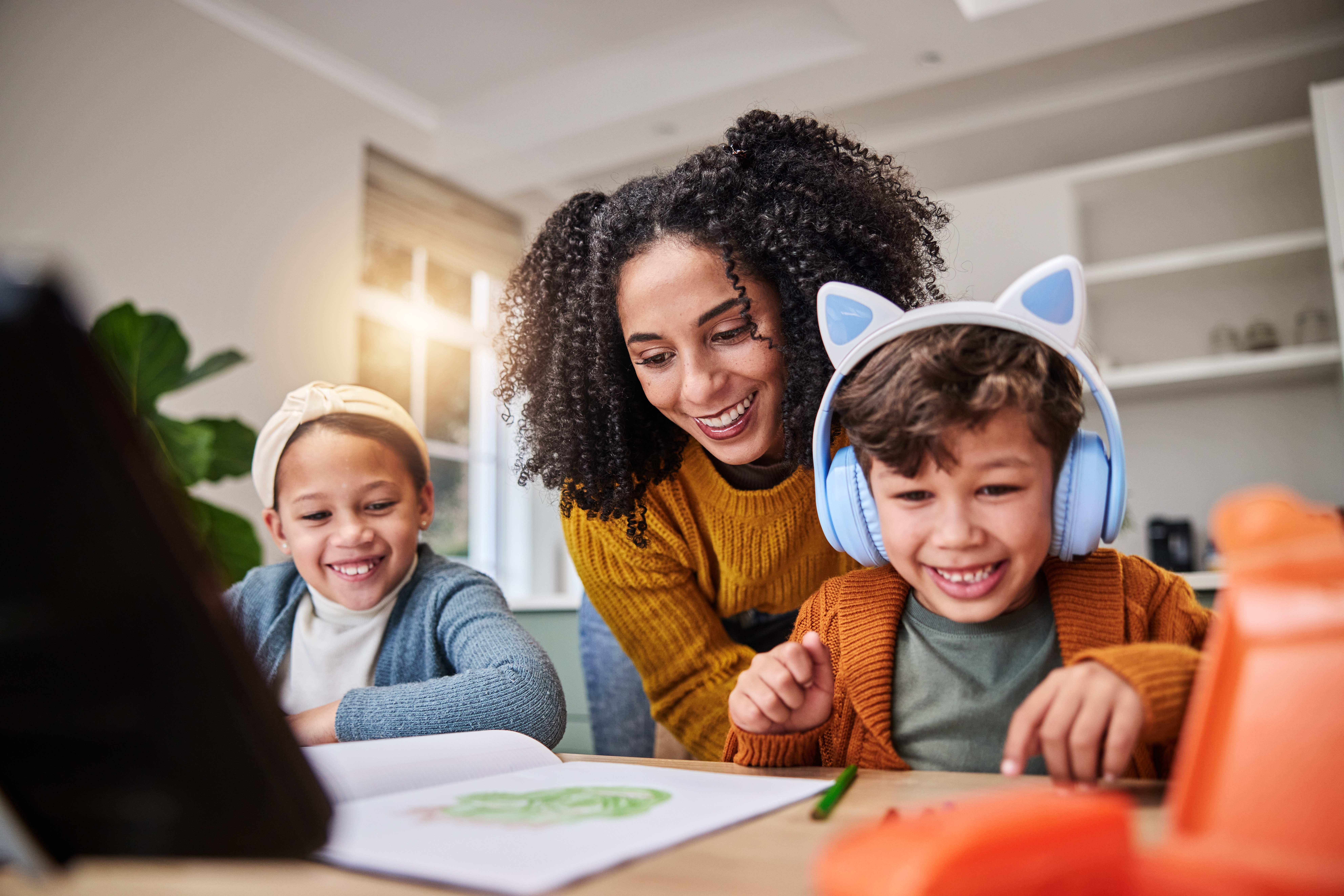 Mom smiles with two children during a creative activity at home, supporting family connection and emotional well-being.
